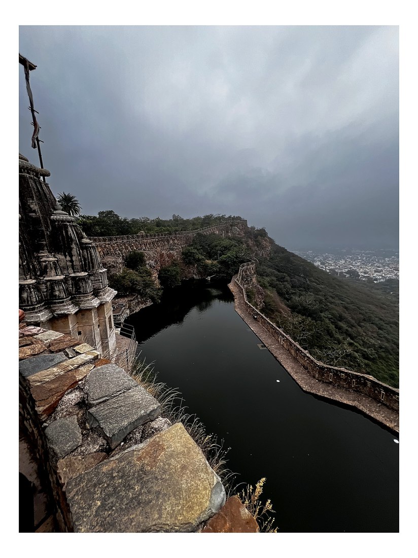 The walls of Chittorgarh Fort above a dark reservoir