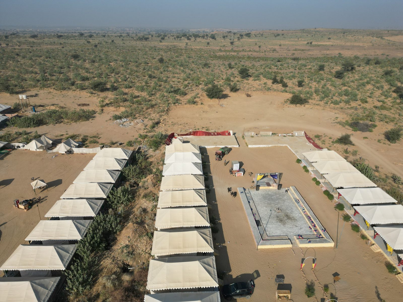 Rows of white guest tents around an open courtyard at a Jaisalmer desert camp
