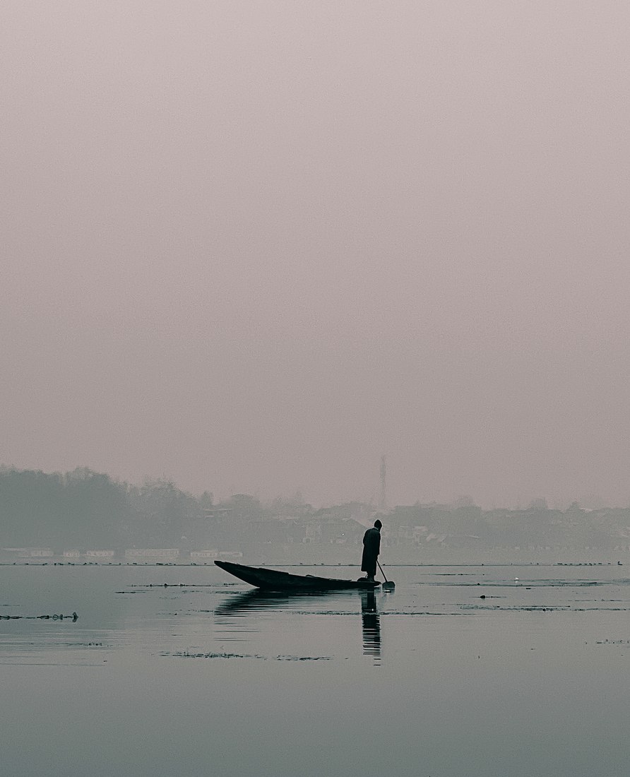 A shikara boatman on the misty waters of Dal Lake, Kashmir